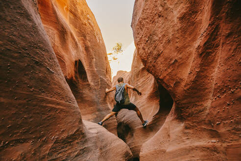 Young man exploring narrow slot canyons in Escalante, during summer - CAVF88926