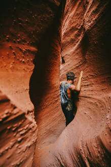 Young man exploring narrow slot canyons in Escalante, during summer - CAVF88928