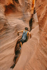 Young man exploring narrow slot canyons in Escalante, during summer - CAVF88929