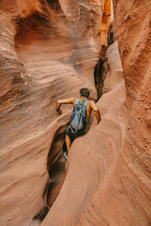 Young man exploring narrow slot canyons in Escalante, during summer - CAVF88929