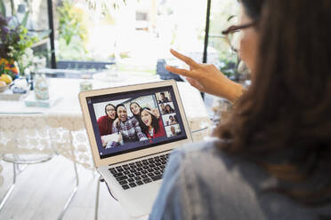 Woman video conferencing with family and friends at laptop screen - CAIF29512