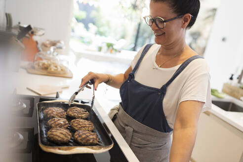 Frau kocht Hamburger auf dem Küchenherd - CAIF29530