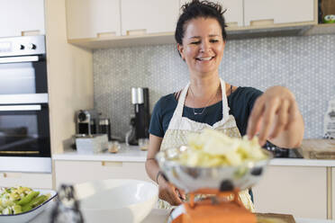 Lächelnde Frau wiegt Äpfel zum Backen in der Küche - CAIF29567