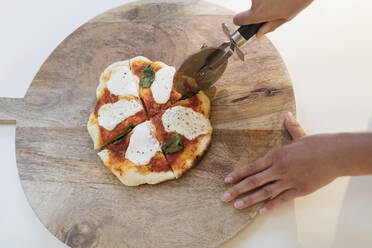 Frau schneidet frische hausgemachte Pizza auf einem Schneidebrett - CAIF29580