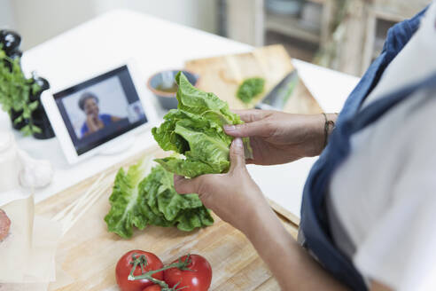 Frau beim Kochen und Videochatten mit digitalem Tablet in der Küche - CAIF29619