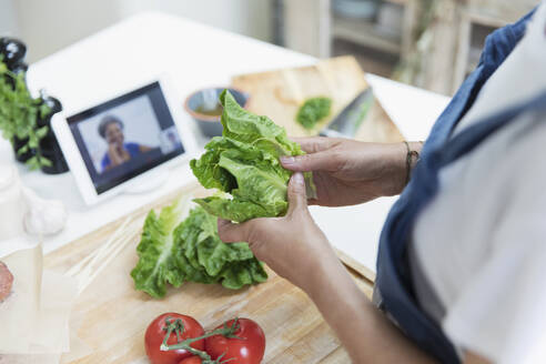 Woman cooking and video chatting with digital tablet in kitchen - CAIF29619