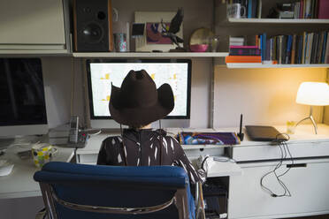 Junge mit Cowboyhut, der zu Hause am Computer im Büro arbeitet - CAIF29654