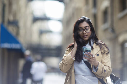 Geschäftsfrau benutzt Smartphone auf dem Bürgersteig - CAIF29673