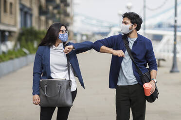 Geschäftsleute mit Gesichtsmasken, die sich auf der Straße mit den Ellenbogen berühren - CAIF29675