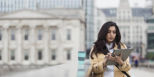 Businesswoman using digital tablet on city bridge - CAIF29695