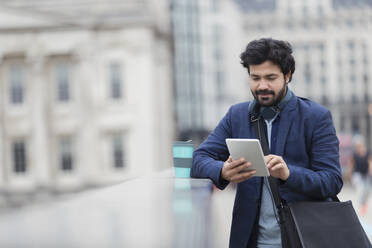 Geschäftsmann benutzt digitales Tablet auf einer Brücke in der Stadt - CAIF29700