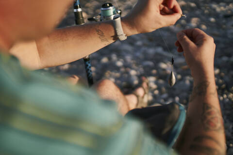 Close-up of mid adult man preparing fishing road at beach stock photo