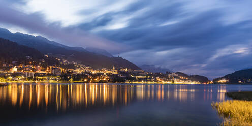 Schweiz, Kanton Graubünden, St. Moritz, Panorama des St. Moritzersees und der beleuchteten Stadt im Engadin in der Abenddämmerung - WDF06275