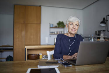 Ältere Frau arbeitet am Laptop, während sie zu Hause sitzt - RBF07849