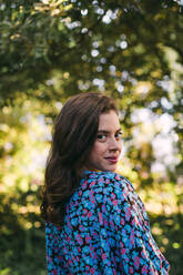 Close-up of young woman standing against trees in park - DCRF00860