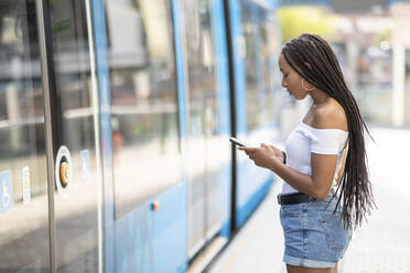 Junge Frau telefoniert in einer Straßenbahn in der Stadt - WPEF03365