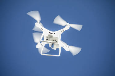 Niedriger Blickwinkel auf eine Drohne, die an einem Tag mit blauem Himmel fliegt. - CAVF89033