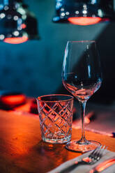 Gläser auf dem Tisch im roten Licht von Infrarotwärmelampen im Restaurant - CAVF89069
