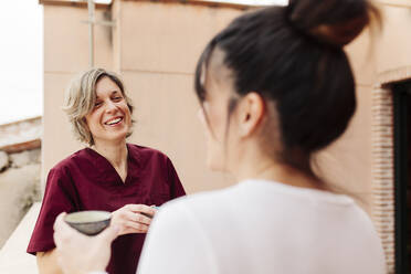 Lächelnde Physiotherapeutin im Gespräch mit einer Frau auf dem Dach - MRRF00443