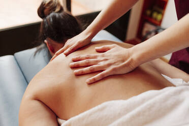 Woman having back massage while lying on stretcher - MRRF00459