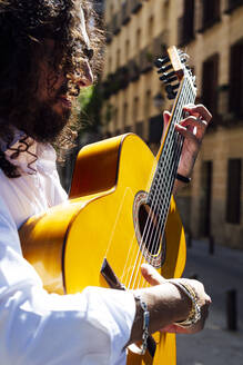 Gitarrist spielt Gitarre, während er auf der Straße in der Stadt steht - JCMF01413