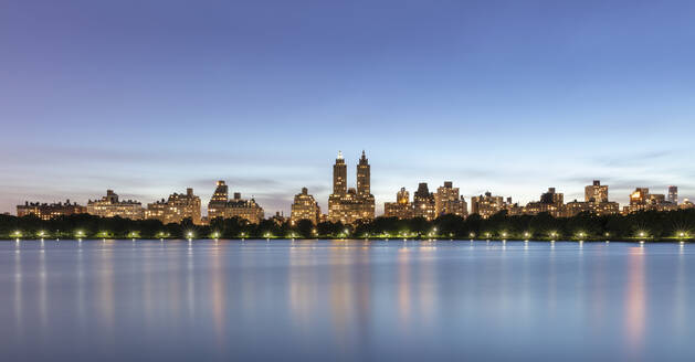 USA, New York, New York City, Manhattan skyline illuminated at dusk seen across Jacqueline Kennedy Onassis Reservoir - AHF00076