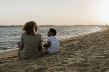 Großmutter und Enkel im Gespräch miteinander am Strand bei Sonnenuntergang - ERRF04355