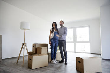 Couple standing on floor with cardboard boxes - MJFKF00643