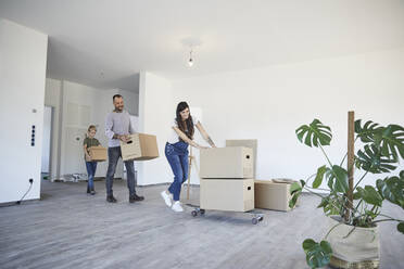 Familie schiebt Kartons auf Skateboard im neuen Haus - MJFKF00652