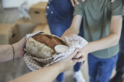 Ausgeschnittenes Bild einer Hand mit Lebensmitteln für die Familie beim Umzug in ein neues Haus - MJFKF00661