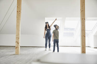 Mother and son wearing virtual reality simulator while standing in domestic room - MJFKF00674