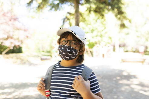 Schoolboy wearing mask standing on footpath - VABF03465