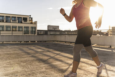 Weibliche Athletin läuft auf einer Gebäudeterrasse in der Stadt - UUF21375