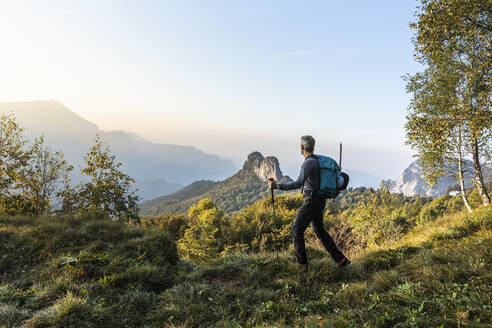 Männlicher Wanderer, der bei Sonnenaufgang auf einem Berg gegen den Himmel läuft, Orobie, Lecco, Italien - MCVF00583