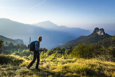 Männlicher Wanderer mit Stock auf einem Berg gegen den Himmel bei Sonnenaufgang, Orobie, Lecco, Italien - MCVF00589