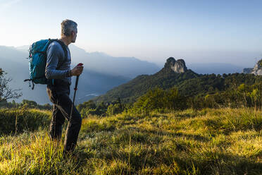 Männlicher Wanderer mit Rucksack und Stock auf einem Berg gegen den Himmel stehend, Orobie, Lecco, Italien - MCVF00592