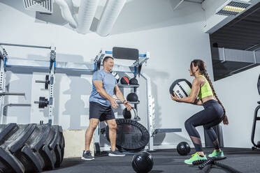 Männliche und weibliche Athleten trainieren mit einem Medizinball im Fitnessstudio - VTF00630