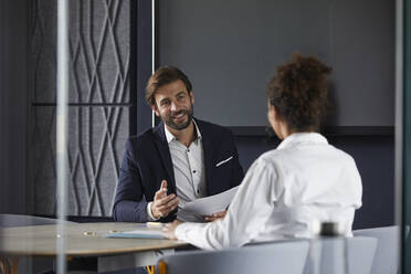 Smiling businessman discussing with colleague in meeting at office - RBF07873