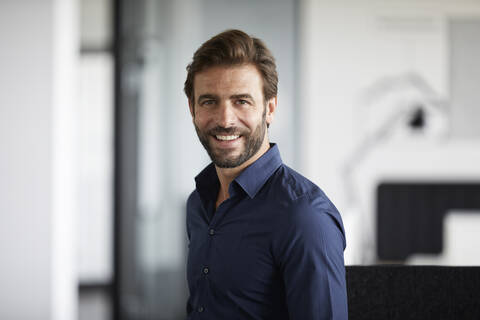 Businessman smiling while standing at office stock photo