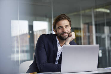 Businessman with head in hands leaning on desk while sitting in office - RBF07925