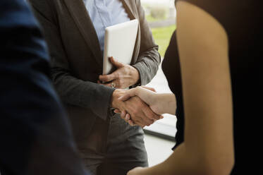 Close-up of business people giving handshake in office - BMOF00402