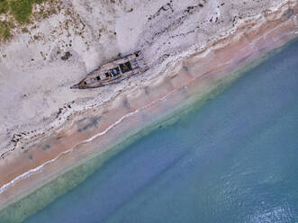 Luftaufnahme eines verlassenen Bootes, das am Sandstrand der Lukin-Bucht verrottet - KNTF05281
