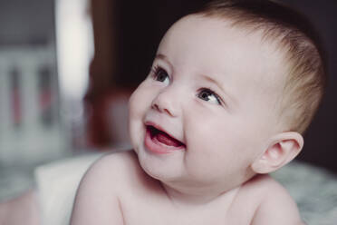 Close-up of cute shirtless baby girl looking away at home - EBBF00759