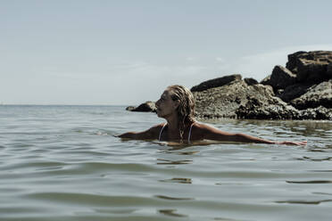 Ältere Frau schwimmt im Meer gegen den Himmel an einem sonnigen Tag - ERRF04383