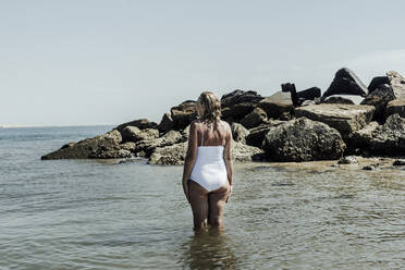 Ältere Frau in Badekleidung steht im Meer gegen klaren Himmel im Sommer - ERRF04388