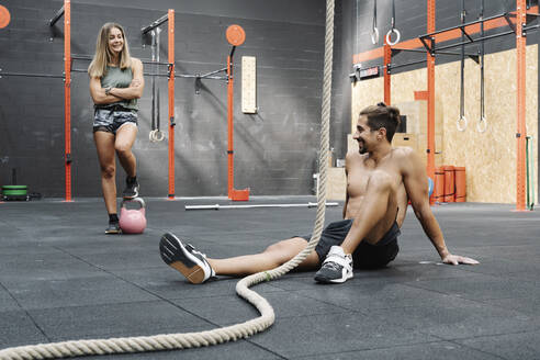 Lächelndes Paar beim Ausruhen nach dem Training im Fitnessstudio - JCZF00227