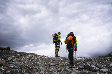 Männliche Freunde wandern auf einem Berg gegen den bewölkten Himmel im Stilfserjoch-Nationalpark, Italien - MCVF00607
