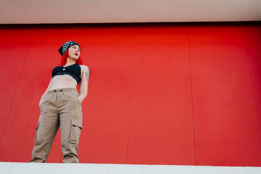 Junges Mädchen mit roten Haaren und einem lgbt-Anhänger auf einem roten Hintergrund - CAVF89108