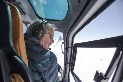 Ein Hubschrauberpilot sucht einen Landeplatz in den schneebedeckten Bergen. - CAVF89200
