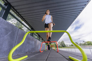 Sportlerin beim Training über kleine Hürden - STSF02619